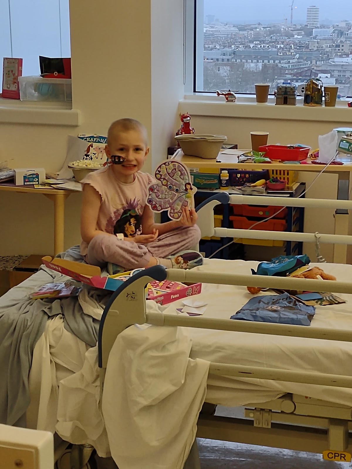A young female neuroblastoma patient smiling and sitting on a hospital bed