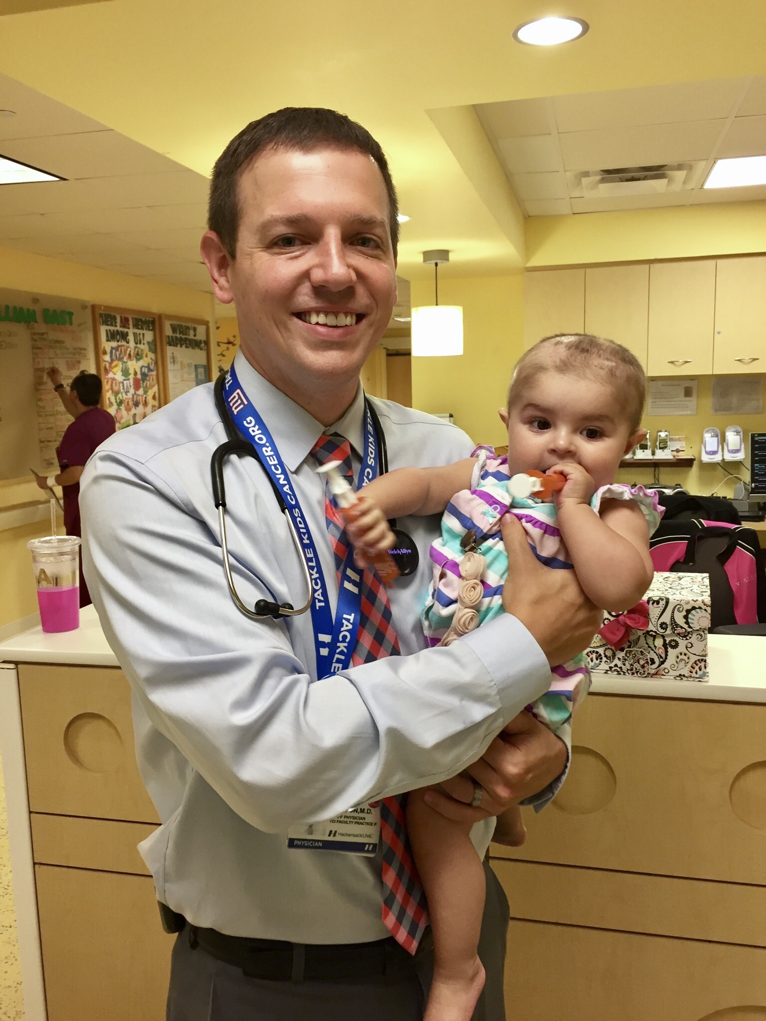 Dr. Derek Hanson in a hospital holding a female infant with ETMR brain cancer 