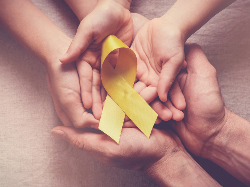 adult and children hands holding yellow gold ribbon