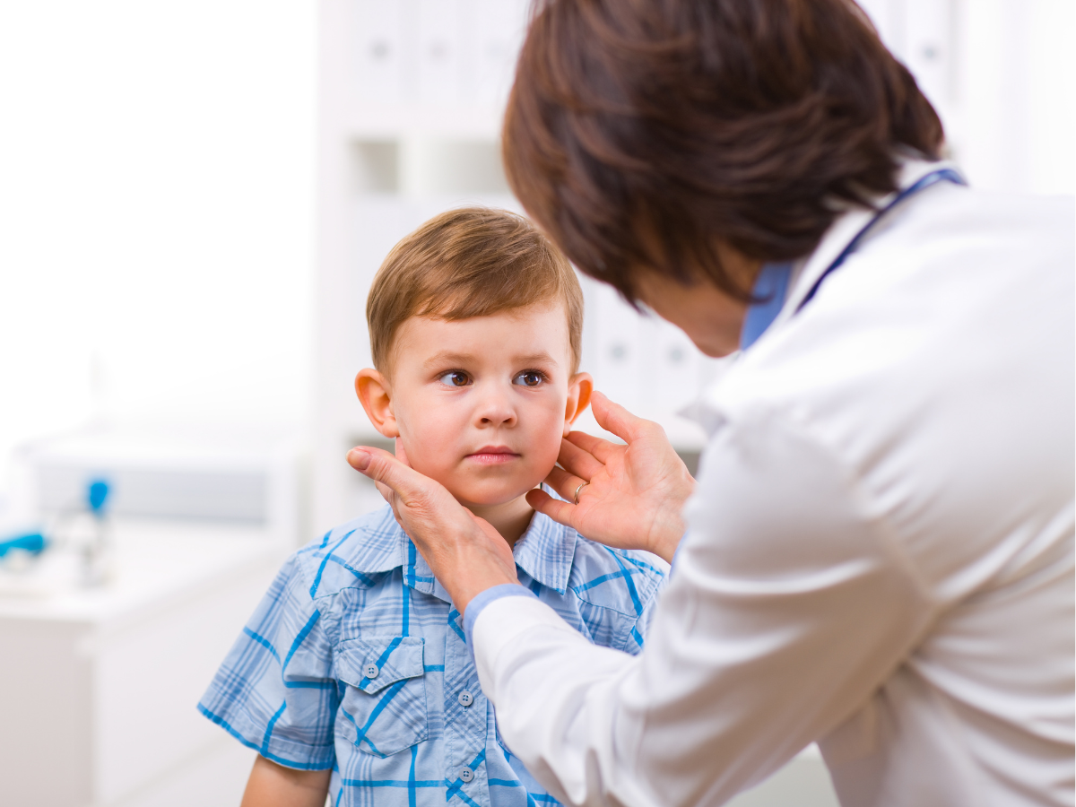 Senior female doctor examining little child boy